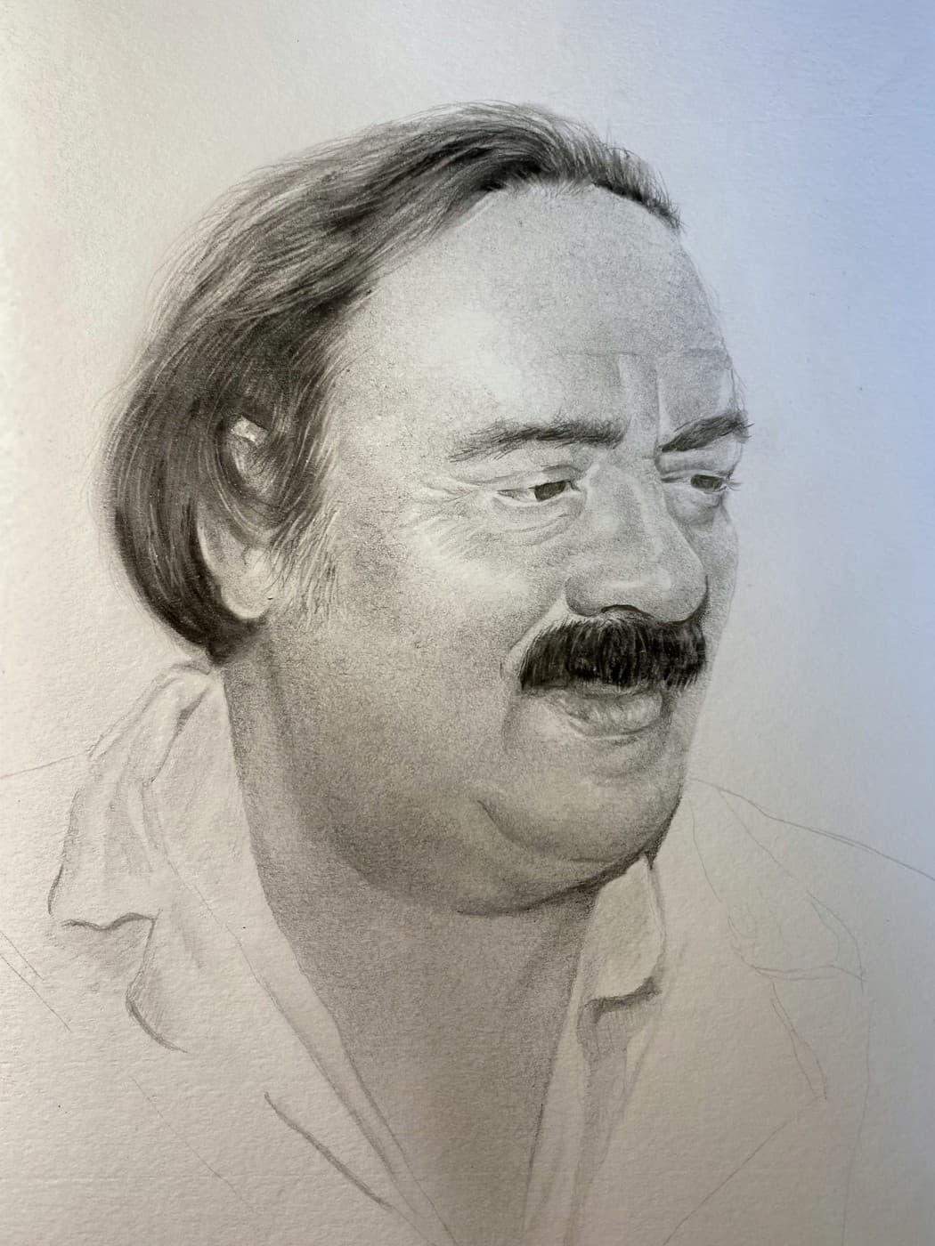 Pencil portrait of a smiling man with a mustache.